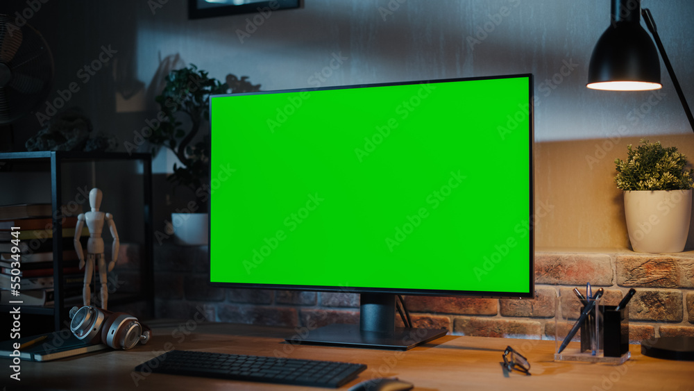 Poster modern personal computer monitor with green screen mock up display standing on the desk with keyboar