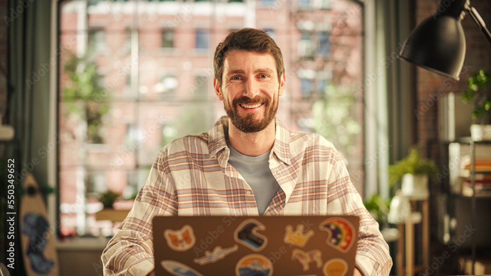 Poster handsome bearded young adult man having an online conversation on a laptop computer in creative offi