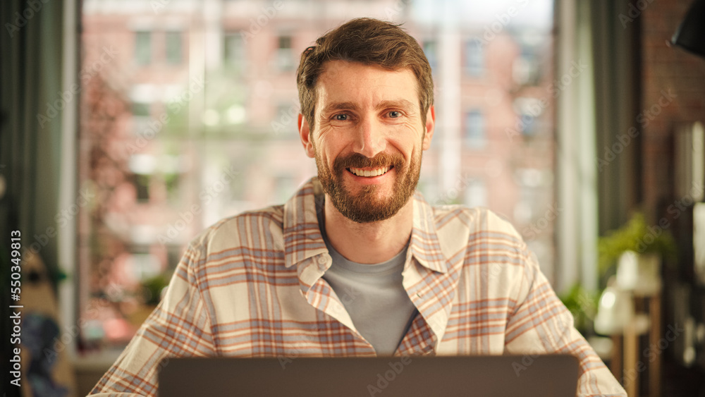 Poster portrait of a happy handsome caucasian man working on laptop computer in stylish cozy living room. f