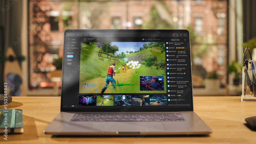 Poster laptop computer display with game live streaming platform standing on wooden table with a notebook i