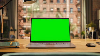 Laptop Computer Display with Mock Up Green Screen Standing on a Wooden Desk in Living Room. Chroma...