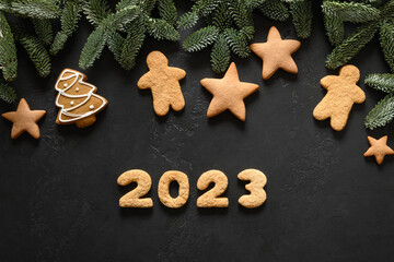 Christmas holidays glazed cookies and date 2023 on a black background. Happy New Year. View from above. Flat lay.