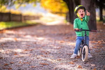 Smiling boy with bicycle showing thumb up gesture