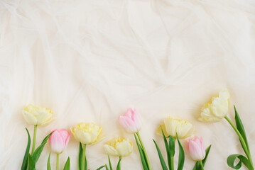 Frame of spring tulip flowers on a beige background with a copy space. Flat lay for wedding day, Easter and Valentine's Day