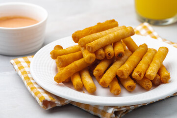 Pinoy cheese sticks are deep-fried snacks composed of sliced processed cheese wrapped in a spring roll wrapper then sprinkled with some cheese powder, with ketchup mayo dip on the side. 