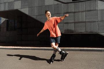 Cheerful young man in roller blades standing on asphalt on street.