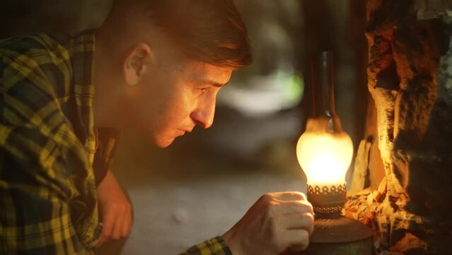 Close-up of a kerosene lamp and male hands adding to the fire. A mystical tunnel and a person illuminates it with a craft paw. High quality 4k footage