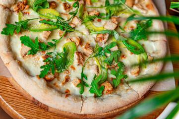 Delicious pizza with grilled chicken, avocado, and arugula.