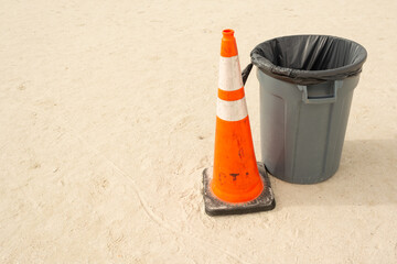 trash can on the beach with a traffic cone