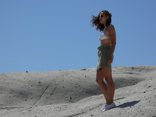 young curly-haired girl posing in a surreal vulcanic moon landscape, Cane Malu at Bosa in Sardinia 