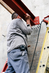 Iron worker installing an I-beam to a concrete retaining wall