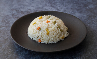 bowl with delicious rice and vegetables on black background, top view