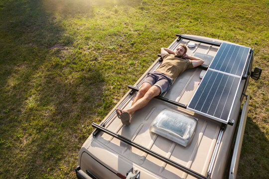 Man relaxing on the roof of a camper van
