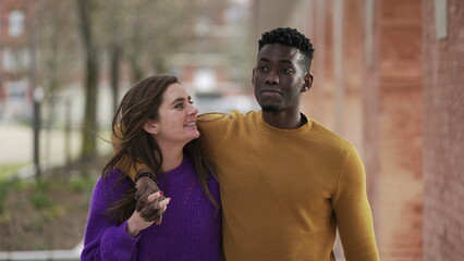 Interracial couple relationship. black man arms around girlfriends walking together outside