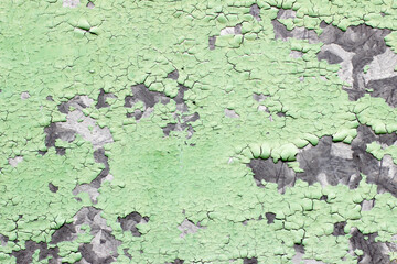 Peeling green paint on the wall. View of a concrete wall with old cracked flaking paint. 