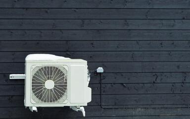 Cooling Air Conditioning Unit and Control System on the black wooden house wall. Heating system