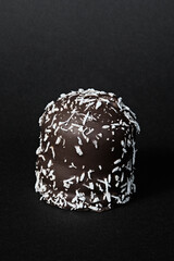 Single chocolote marshmallow with grated coconut with a black background