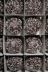 Cardboard box with lots of chocolate marshmallows with grated coconut from above. Eight chocolate marshmallows are fully visible.