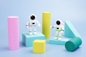 Plastic figurines of an astronauts in a spacesuit and geometric shapes on a blue background....