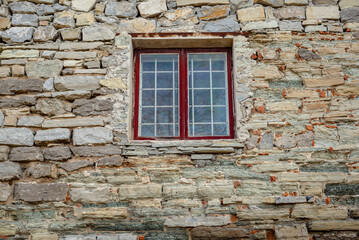 Fototapeta na wymiar Part of the decoration of the facade of the building and the material from which it is built; old stone house and window