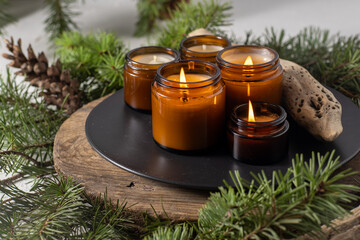 Soy candles burn in glass jars. Comfort at home. Candle in a brown jar. Scent and light. Scented handmade candle. Aroma therapy. Christmas tree and winter mood. Cozy decor. Festive decoration