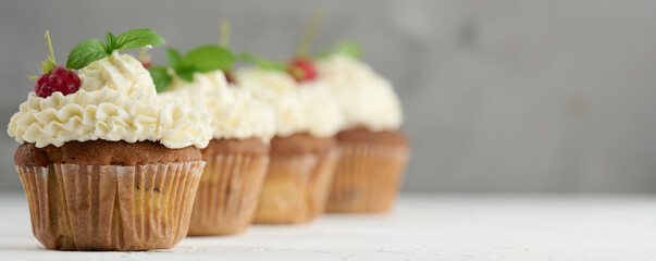 Baked cupcakes with white butter cream on the table, delicious dessert - obrazy, fototapety, plakaty