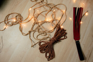 Shibari ropes and flogger  before a session over a wooden floor