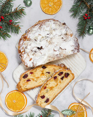 Christmas stollen with candied fruits and dried fruits on a wooden board, next to a spruce branch with a festive atmosphere. Traditional German dessert for Christmas celebration.
