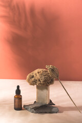 Balance creative bathroom composition with natural sponge, handmade soap,oil  and stones on a terracotta and beige background, shadows from plants. Eco composition, zen, Earth tones