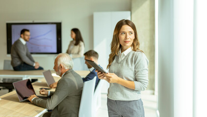 Young business woman at startup office with digital tablet in front of her colleagues as team leader