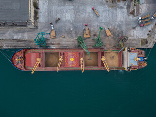 Aerial view of big cargo ship bulk carrier is loaded with grain of wheat in port