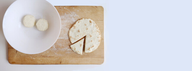 Piadina ready to be tasted on a cutting board with two flour dough. Typical italian dish concept. Top view, flat lay, copy space, banner

