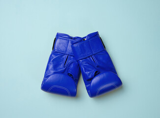 Blue leather boxing gloves on a blue background. Sports equipment, top view