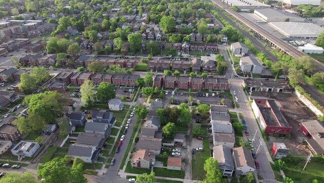 Wide high angle from aerial drone view of lower class urban neighborhood suburb with town houses, student housing, rental property, apartments, city streets, car traffic, and old, low income buildings