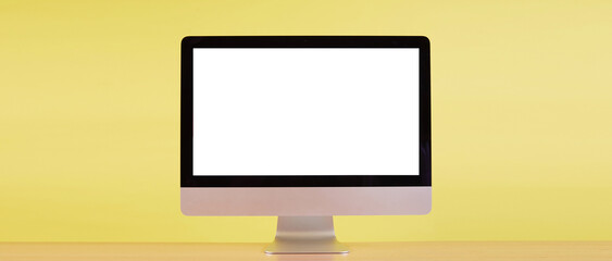 computer monitor with blank screen on wood table with yellow background.