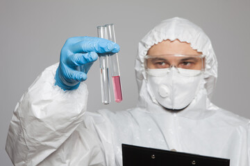 Laboratory worker holding test tubes with substance samples for analysis on gray background. Closeup.