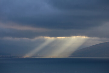 the sun rays shine through the clouds on the sea surface