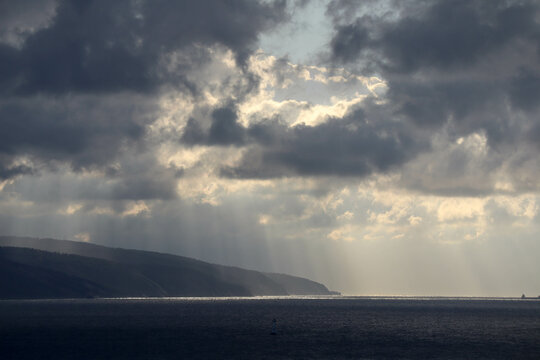 the sun rays shine through the clouds on the sea surface