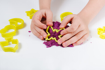 Purple kinetic sand, plastic molds for sand. Child sculpts and plays with sand. Close-up view....