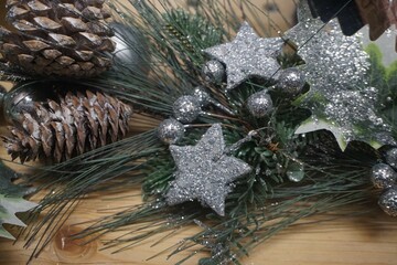 Weihnachtsdekoration mit grünen Tannenzweigen, silbernen kleinen Sternen und Kugeln und Eicheln...