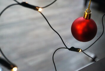 Weihnachtsdekoration mit roter Weihnachtskugel und brennender Lichterkette hinter Glasscheibe am...