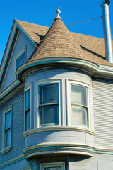 Obraz premium Spire or house turret with green gray wooden slat or pannel exterior with light brown roof with visible windows and chimney vent