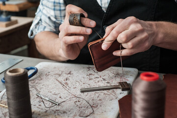 Stitching close-up. Hand sewing of the product. Production of leather products, sewing of bags,...
