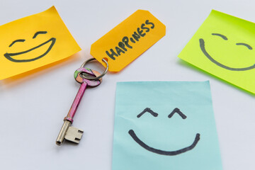 A key to happiness concept with a key and hand drawn happy faces isolated in a white background.