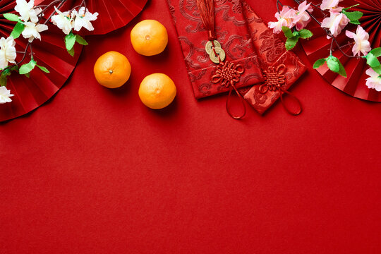 Happy Chinese New Year 2023 concept. Festive composition with oranges, lucky money red envelopes, blossom flowers on red background.