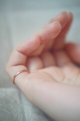 Vertical view of a golden ring on a woman's little finger, on a bright soft background