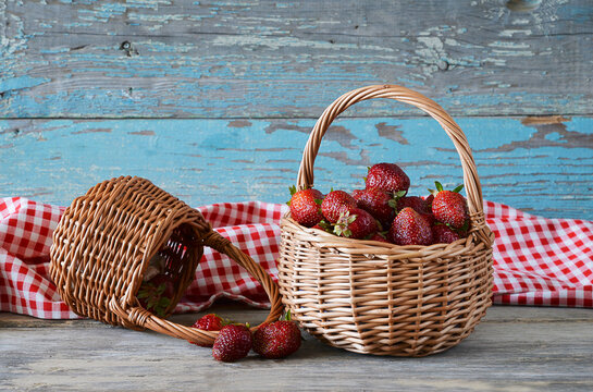 Ripe strawberries in wicker basket on old wooden background
