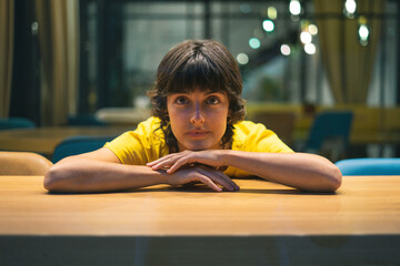 Young woman resting on a table and looking at camera