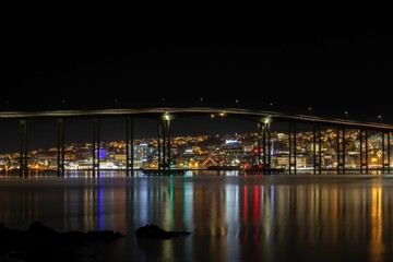 Midnight view of Tromso with colorful city lights and reflection in the sea, Norway