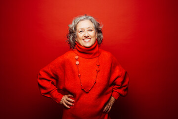Portrait of a Senior smiling woman wearing red clothes over a red background